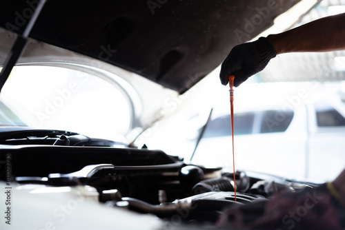 Senior Asian man checking or measuring a vehicle oil engine or engine lubricant level by using oil stick indicator. 