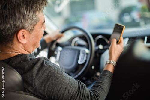 Middle aged man using a smart phone while driving a car