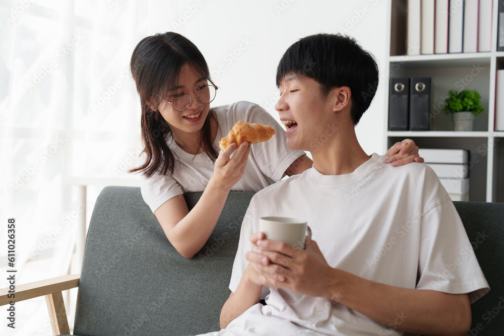 Beautiful asian couple in love and smiling sitting on sofa at morning. Romantic moment, relationships, family concept Beautiful asian couple in love and smiling sitting on sofa at morning. Romantic moment, relationships, family concept