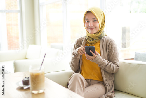 Business asian hijab woman wearing Orange T-shirt holding mobile phone