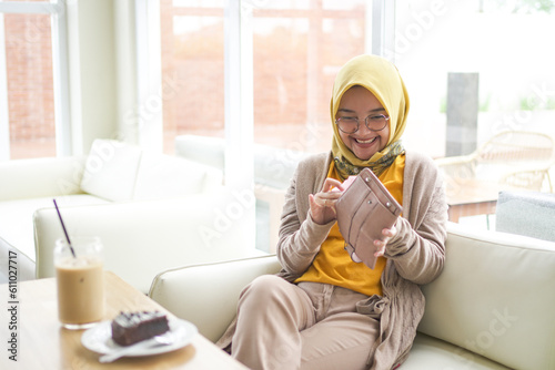 Business asian hijab woman wearing Orange  T-shirt opened something in the wallet show