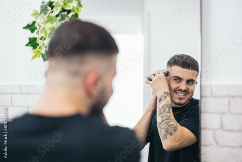 Young barber cutting his hair himself photo