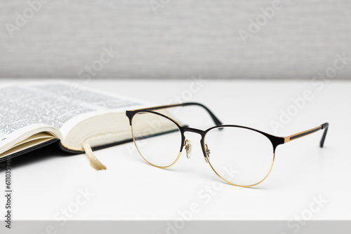 reading glasses lie on the table near the book.