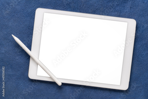 mockup of digital tablet with electronic pencil and a blank isolated screen (clipping path included) against ablue textured art paper photo