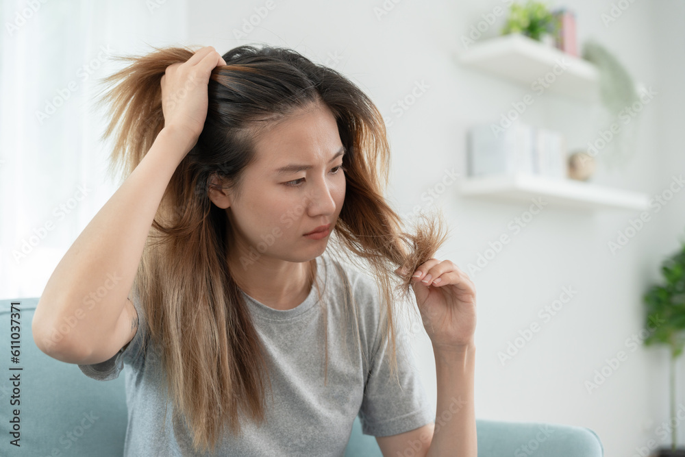Asian woman very sad and upset looking at damaged hair, hair loss, hair thinning problem, vitamin deficiency, baldness, postpartum, biotin, zinc, menstrual or endocrine disorders, hormonal imbalance Asian woman very sad and upset looking at damaged hair, hair loss, hair thinning problem, vitamin deficiency, baldness, postpartum, biotin, zinc, menstrual or endocrine disorders, hormonal imbalance