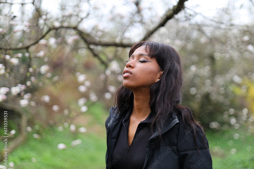 African american girl with closed eyes enjoying the smell of cherry blossoms in the park. African american girl with closed eyes enjoying the smell of cherry blossoms in the park.
