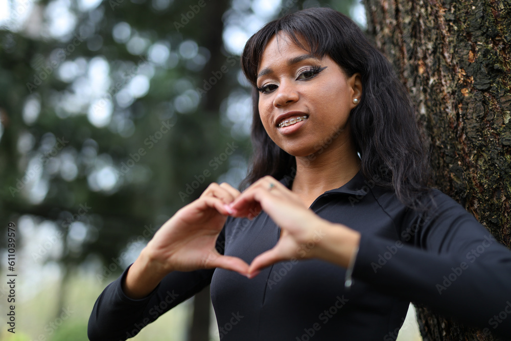 Cute african american girl in black blouse making heart symbol with her hands. Cute african american girl in black blouse making heart symbol with her hands.