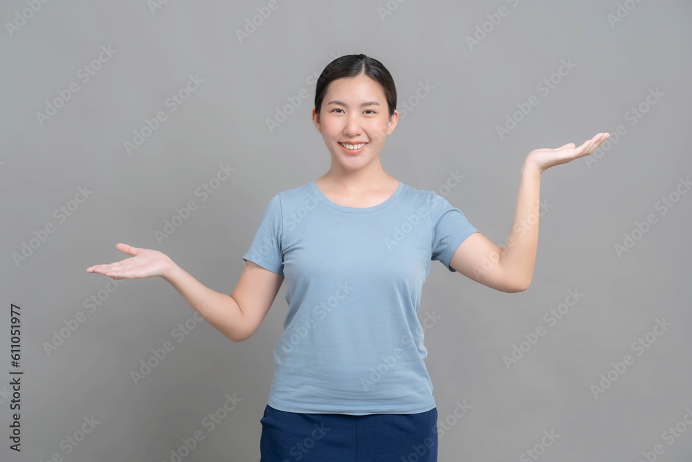Young Asian woman portrait standing smiling and doing different poses in studio against gray background. Young Asian woman portrait standing smiling and doing different poses in studio against gray background.