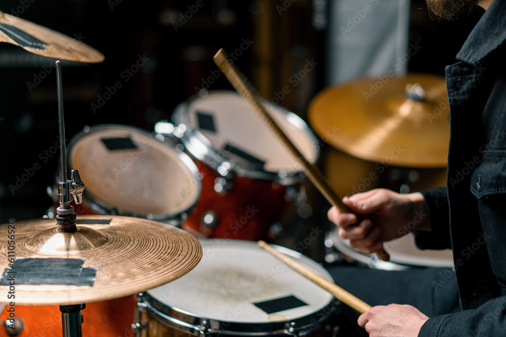 Naklejka premium drummer plays a drum kit in a recording studio at a professional musician rehearsal recording a song beats the sticks on the instrument close-up
