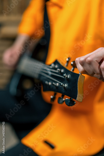 rock performer with electric guitar in recording studio recording playing own track tuning musical instrument strings close-up