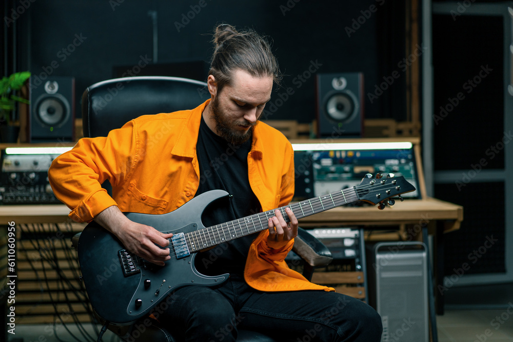 Obraz premium rock performer with electric guitar in recording studio recording playing own track musical instrument strings melody