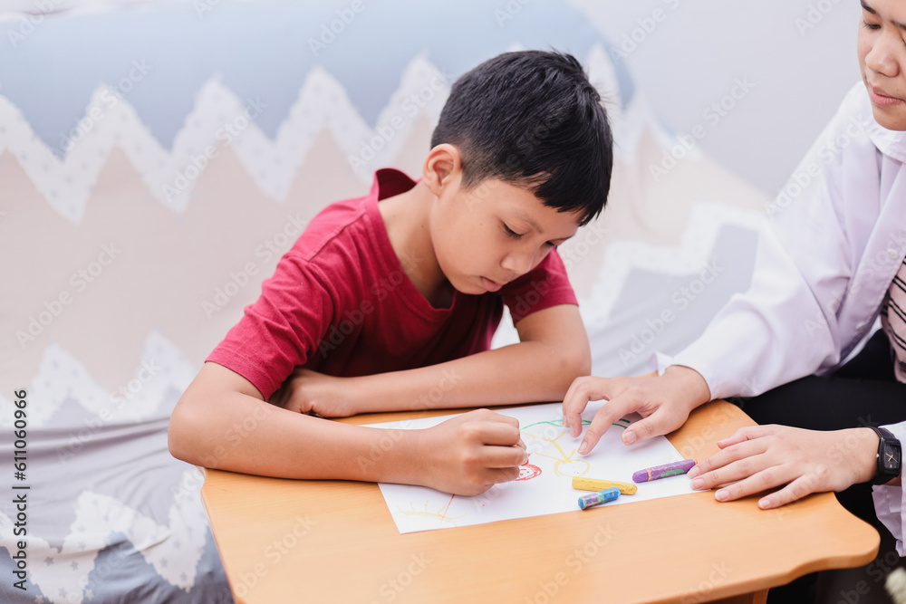 Child psychologist talking to boy while he drawing on white paper. Psychology, psychotherapy, professional counseling mental help for children Child psychologist talking to boy while he drawing on white paper. Psychology, psychotherapy, professional counseling mental help for children