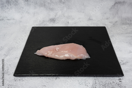 Paris, France - 03 24 2023: French culinary Still Life. Piece of chicken breast placed on a black tile top.. photo