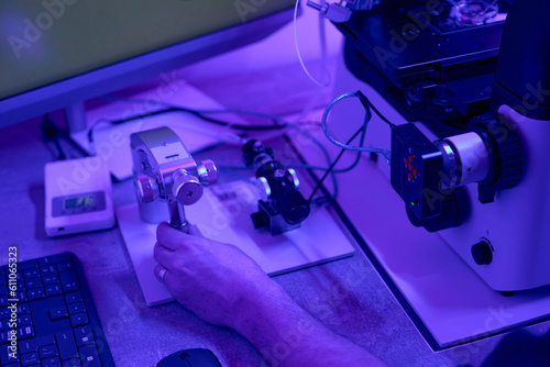 Biotechnician adjusting micromanipulators on microscope in clinic