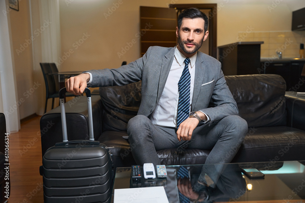 Fototapeta premium Satisfied man in a business suit sits on cozy sofa