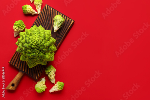 Composition with romanesco cabbage and wooden board on red background photo