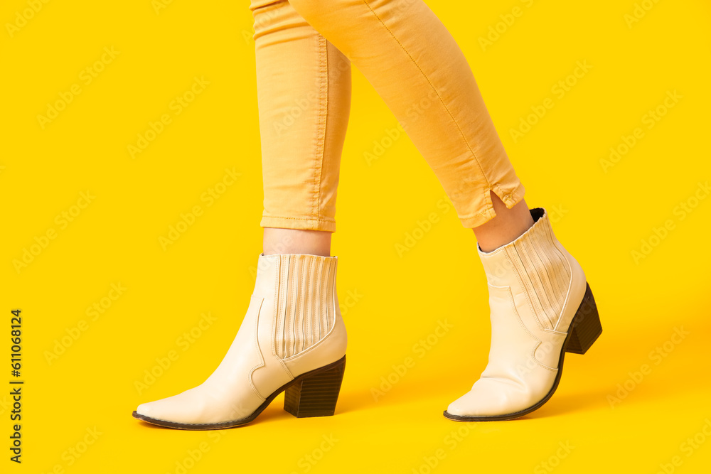 Female legs in stylish shoes on yellow background, closeup Female legs in stylish shoes on yellow background, closeup
