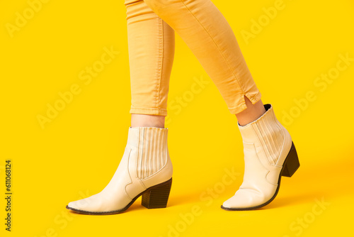 Female legs in stylish shoes on yellow background, closeup