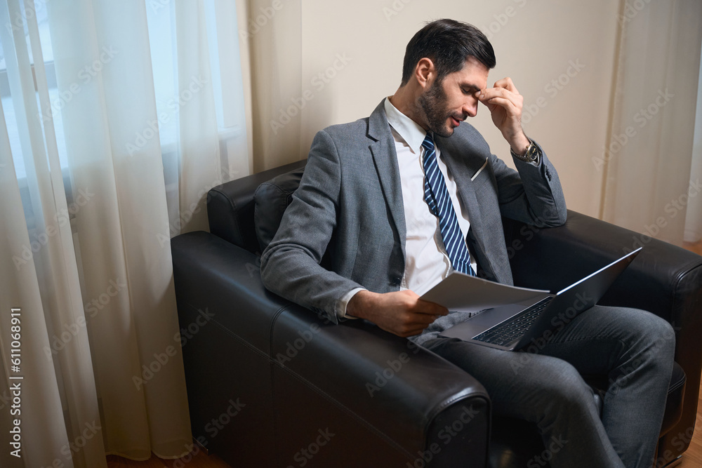 Tired businessman sits in a leather chair