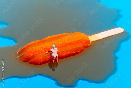 miniature bather man on a melting orange popsicle photo