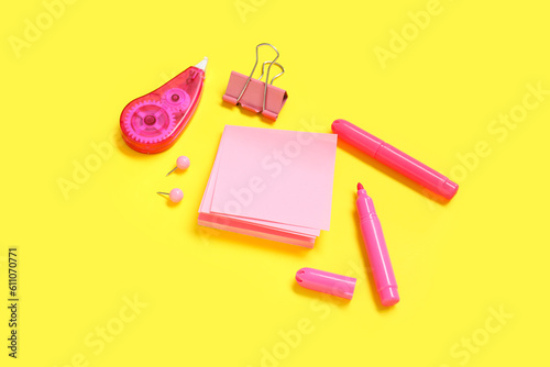 Sticky notes with different stationery supplies on yellow background © Pixel-Shot