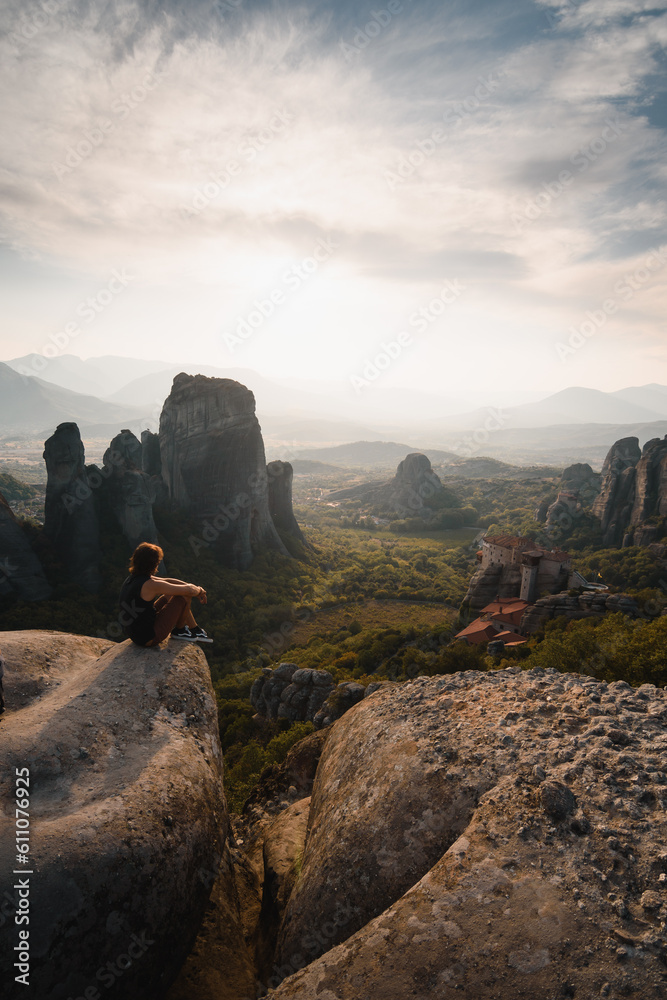Man sitting enjoying at sunset the beautiful landscape of the monasteries on rocks of Meteora. During his tourist trip through Greece.