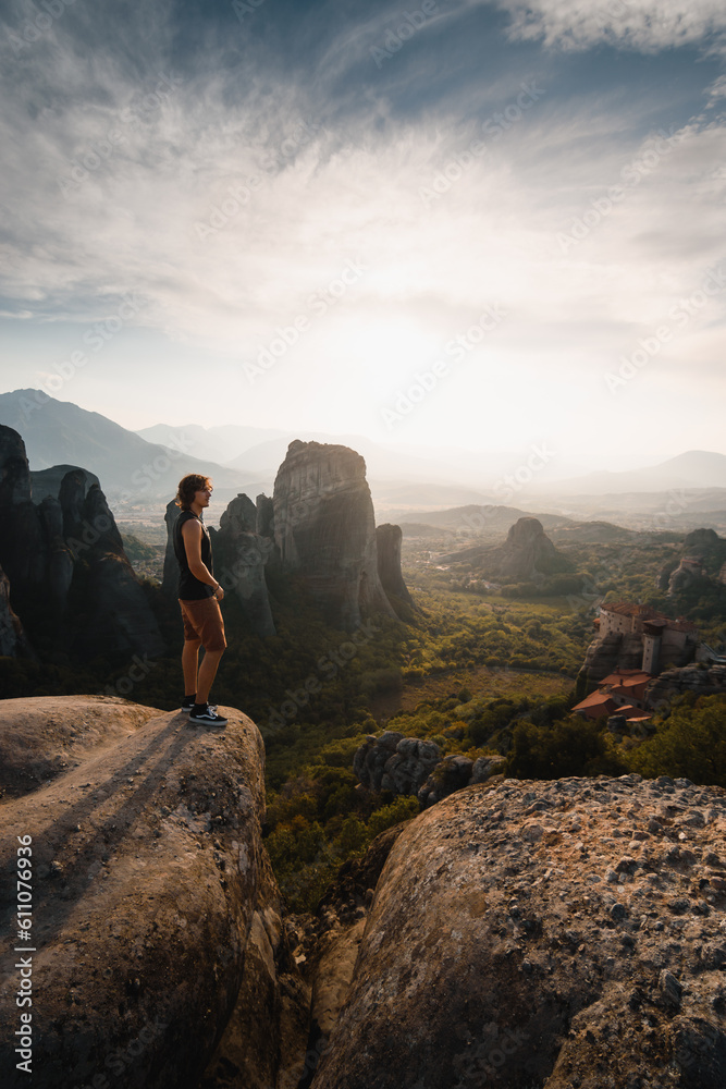 Man standing getting inspired by the beautiful sunset at the Meteora rock monasteries during his adventure in Greece.