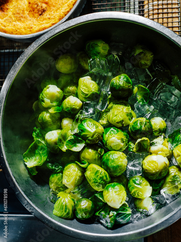 Iced blanched brussels sprouts in a stainless steel bowl