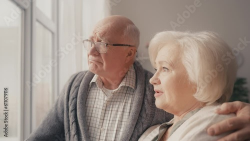 Sad senior husband and wife looking out the window, youth gone, nostalgia photo