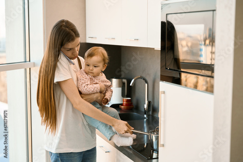 Beautiful woman is preparing baby food with a baby in her arms