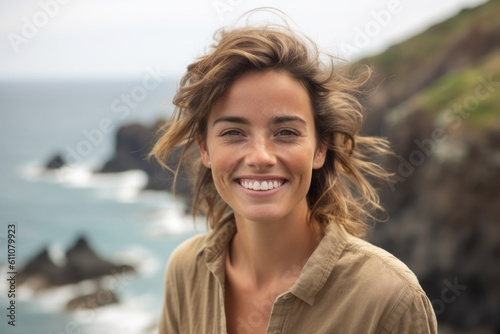 Close-up portrait photography of a joyful girl in her 30s with crossed arms against a scenic ocean cliff background. With generative AI technology
