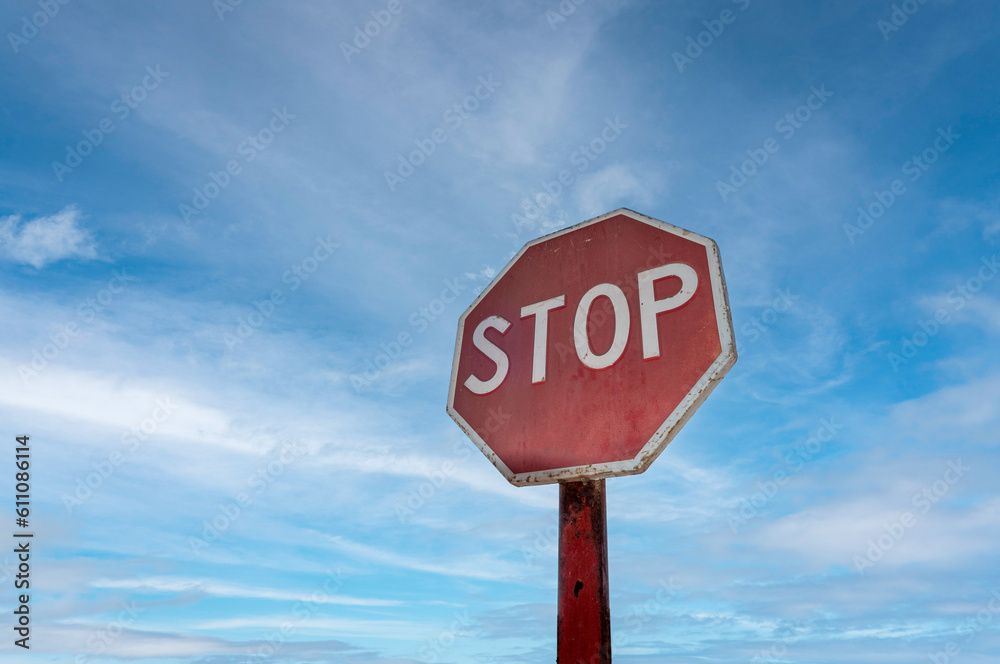 Red octagonal stop sign against a blue sky background.