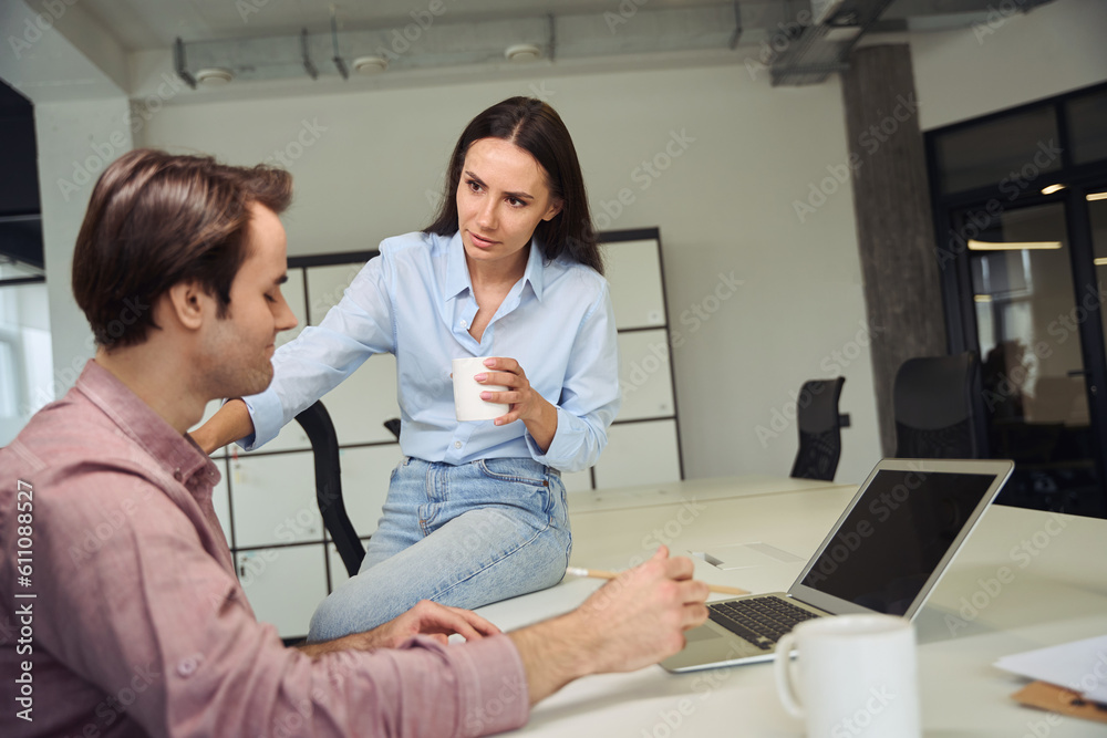 Office worker consoling despondent coworker in workplace during tea break