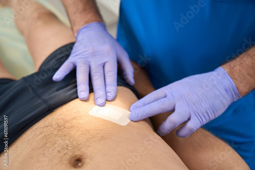 Male hands of doctor applying patch to patient after injection