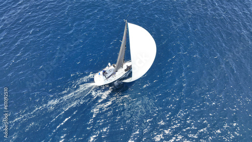 Aerial drone photo of beautiful sailing boat with white sails cruising deep blue Aegean sea, Greece