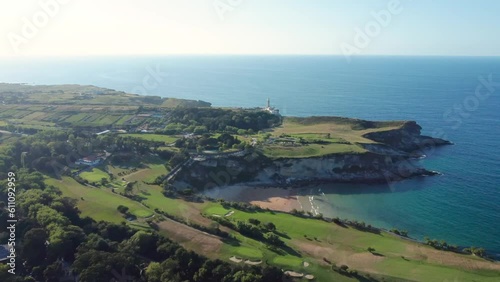 Aerial view of golf courses on the outskirts of Santander city. Beautiful sunset colours. In the center is Playa de Mataleñas, an beautiful small beach. In background Lighthouse Cabo Mayor. Descending