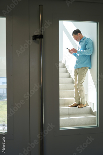 Male standing on stairs in hospital and looking at phone