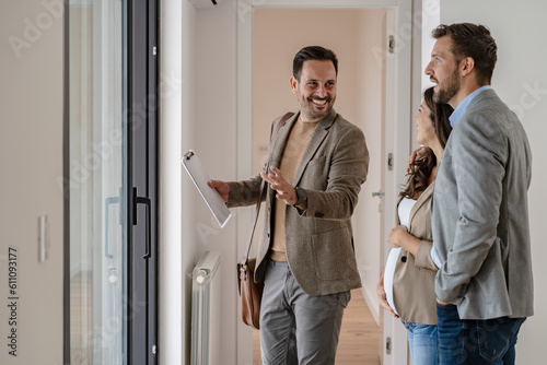 A young couple with a real-estate agent visiting an apartment for sale or for rent. Married couple buying an apartment. Real estate concept.