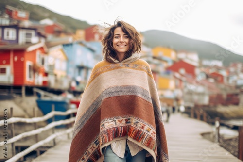 Murais de parede Lifestyle portrait photography of a joyful girl in her 30s wearing a unique poncho against a picturesque fishing village background