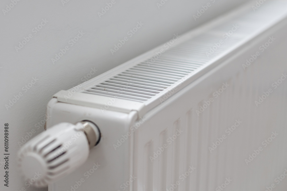 White heater with radiator and a modern thermostat on the wall in an apartment White heater with radiator and a modern thermostat on the wall in an apartment