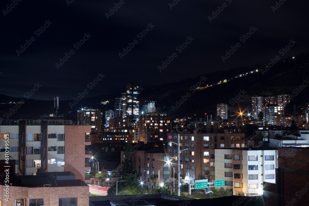 Bogota night cityscape with skyscrapers and oriental mountain range at background