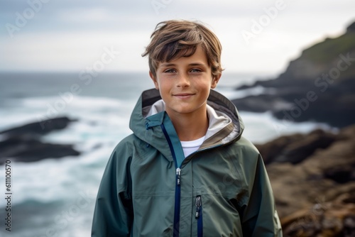 Lifestyle portrait photography of a satisfied kid male wearing a lightweight windbreaker against a scenic ocean cliff background. With generative AI technology © Markus Schröder