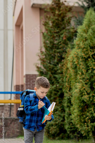Little first grader with backpack looking the copybook, going home from school