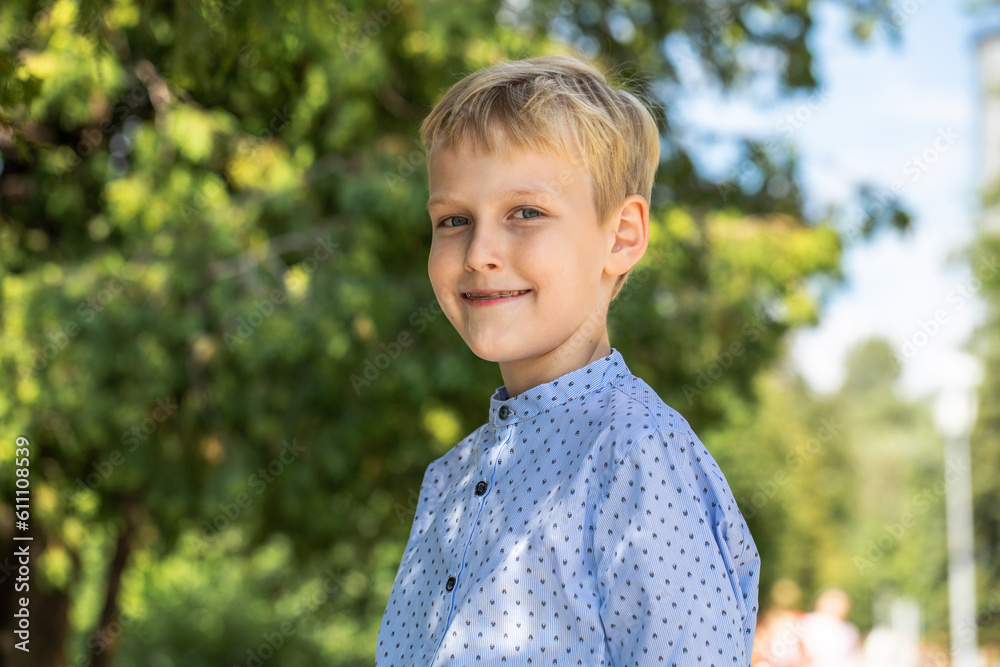 Portrait of a little boy in a blue shirt posing in a summer park Portrait of a little boy in a blue shirt posing in a summer park