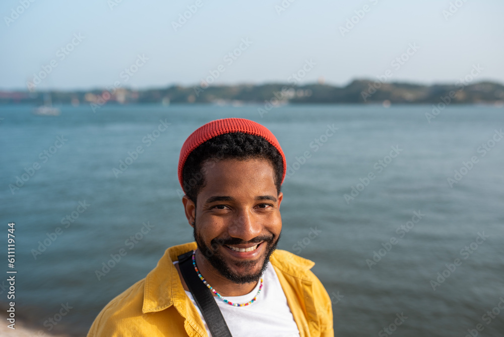 Smiling cheerful young handsome African man standing in front of the sea Smiling cheerful young handsome African man standing in front of the sea