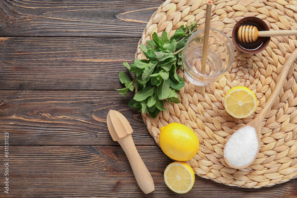 Wicker mat with glass, lemons and mint on brown wooden background Wicker mat with glass, lemons and mint on brown wooden background