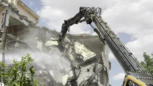 Demolition by a demolition machine. Spraying water to prevent dust formation. 