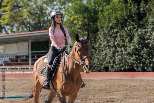 Close up of a young woman riding a horse in an equestrian center