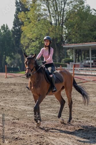 Vertical shot of a young woman riding a horse in an equestrian center
