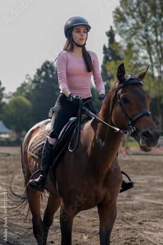 Close up on a young woman wearing a helmet who is riding a horse in an equestrian center